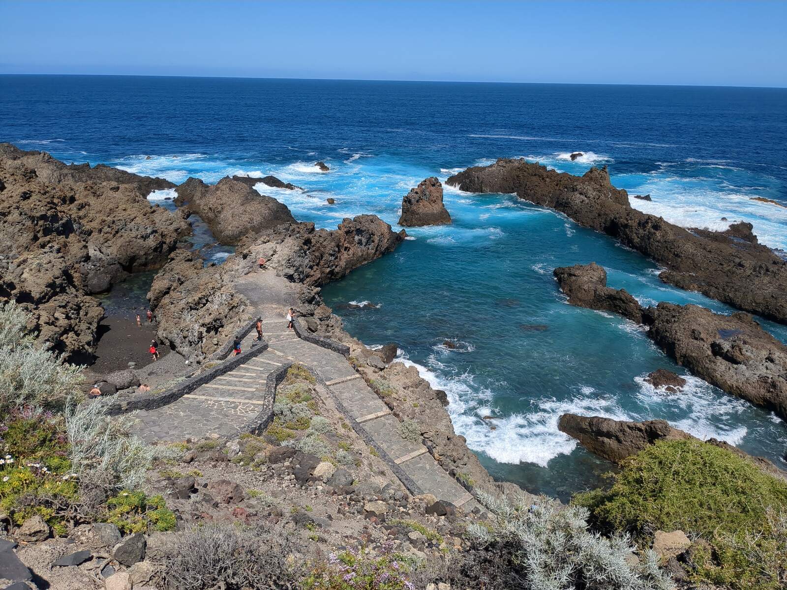 Türkisblaues Meerwasser zwischen dunklen Lavafelsen an der Küste Teneriffas